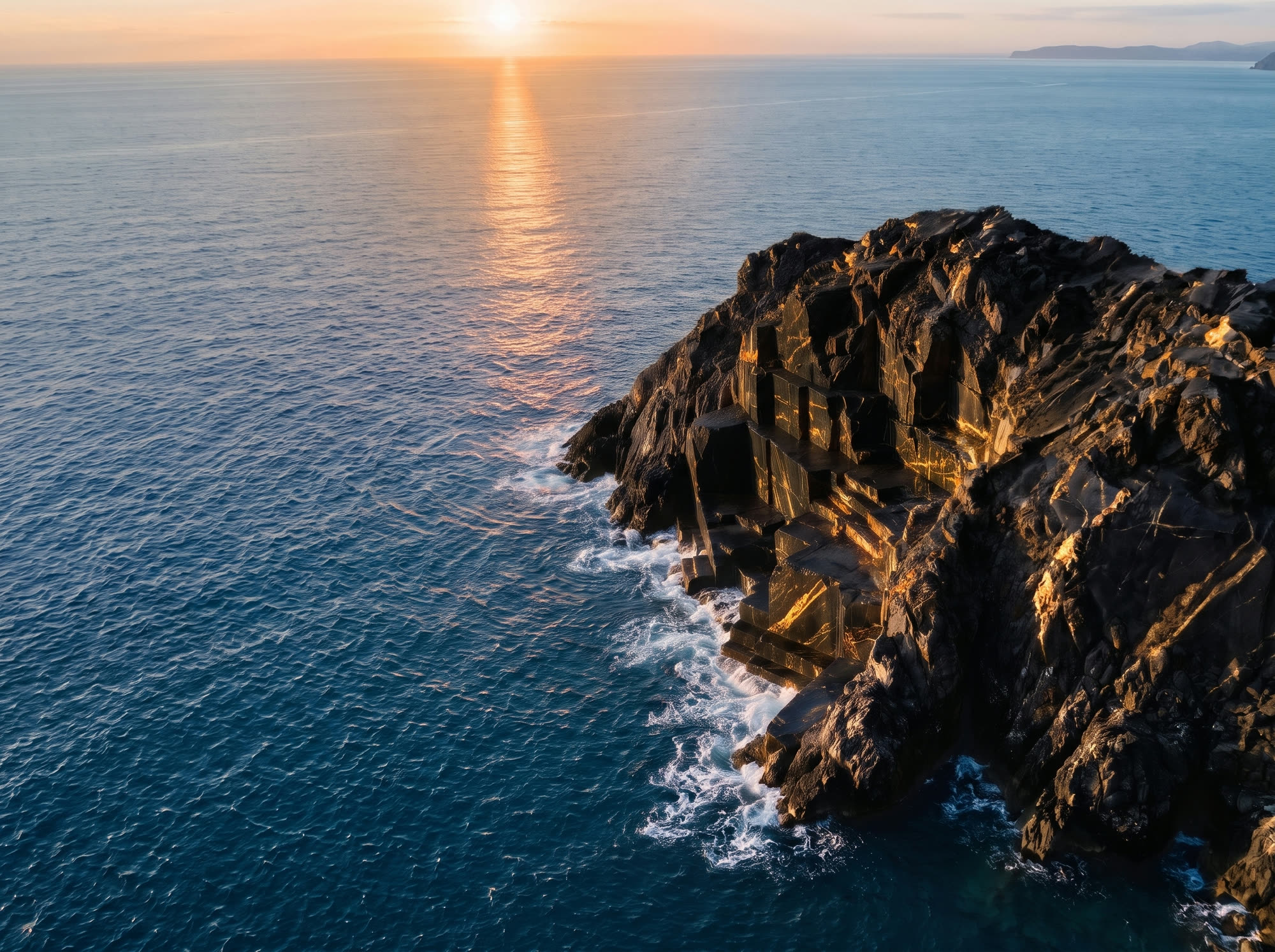 Scogliera di marmo Portoro nero sul mare, luce dorata del tramonto